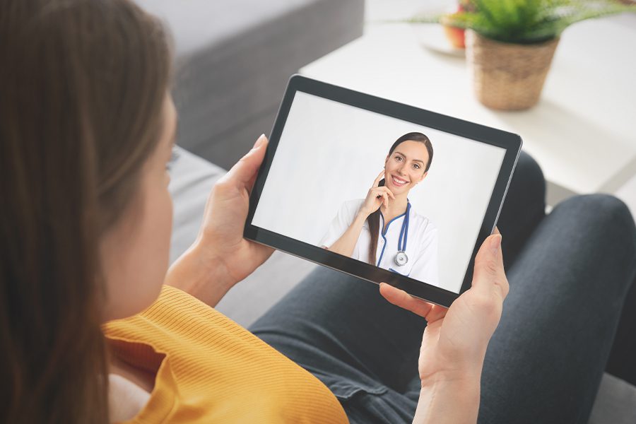 Group Telemedicine - Blurred View of Patient Using Tablet for Healthcare Diagnosis with Virtual Doctor