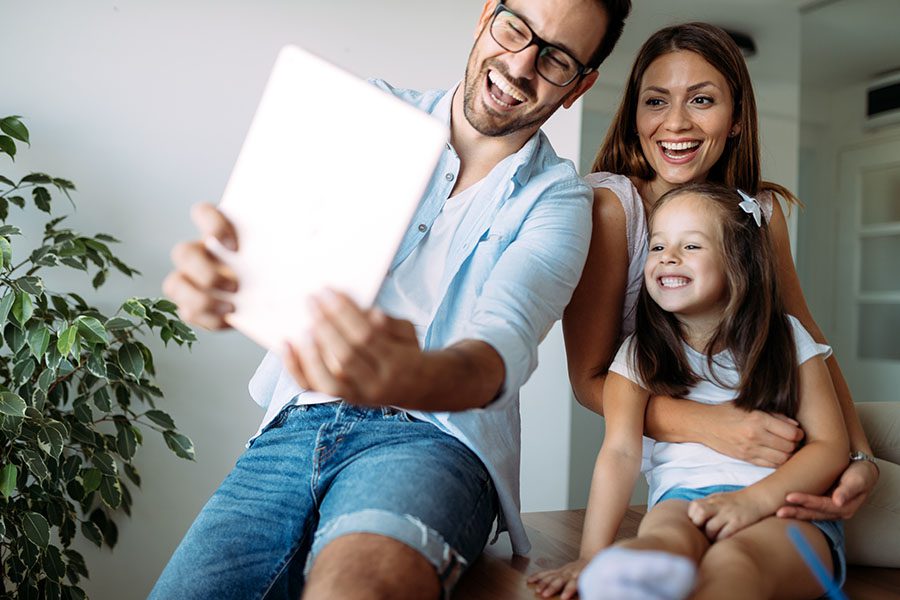 Client Center - Portrait of a Cheerful Family with a Young Daughter Sitting at Home Using a Tablet