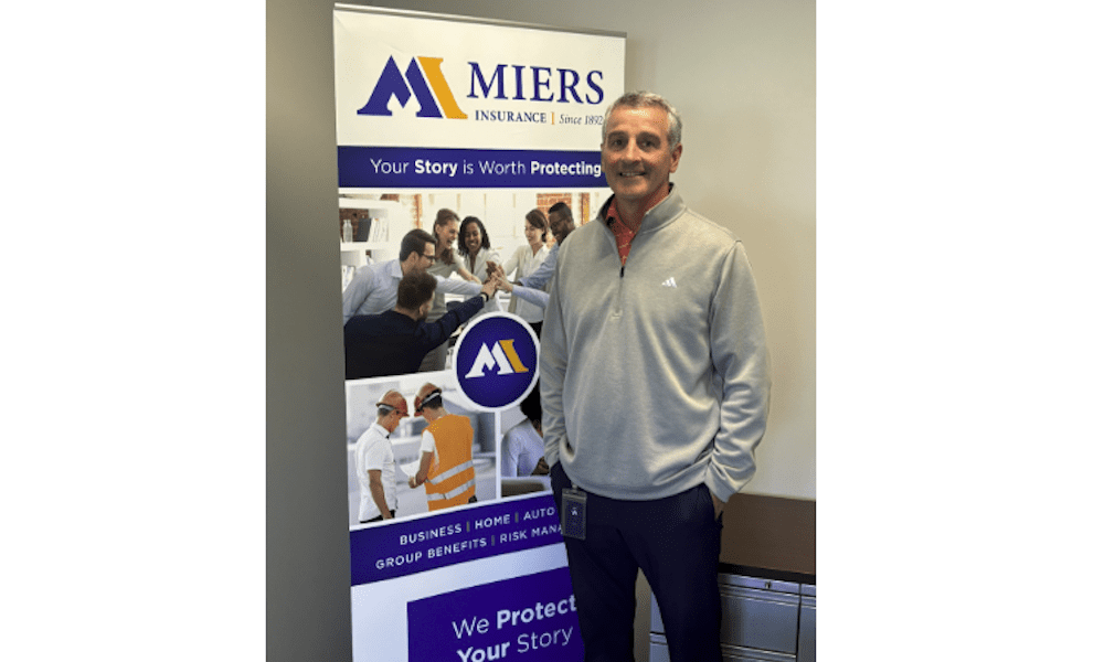 Miers Insurance Welcomes Bill Heydt as Benefits Consultant - Photo of Bill Heydt smiling posed infront of the Miers Insurance banner